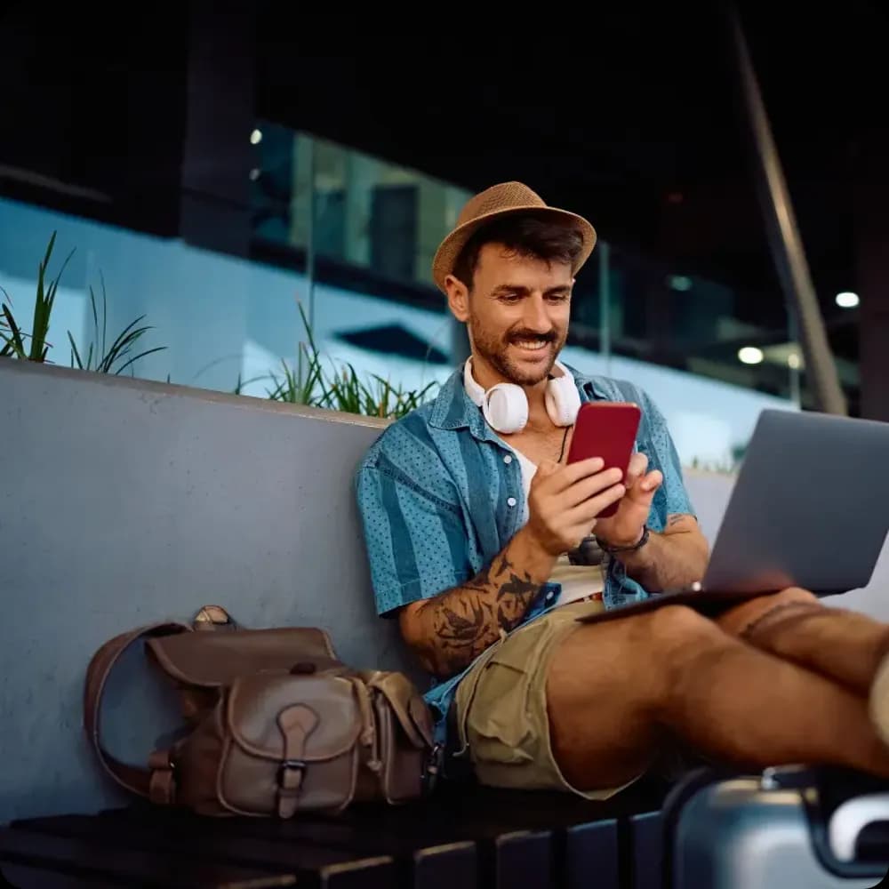 Happy traveler using laptop and phone